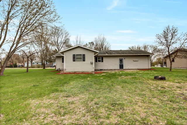 back of house featuring a lawn and an outdoor fire pit