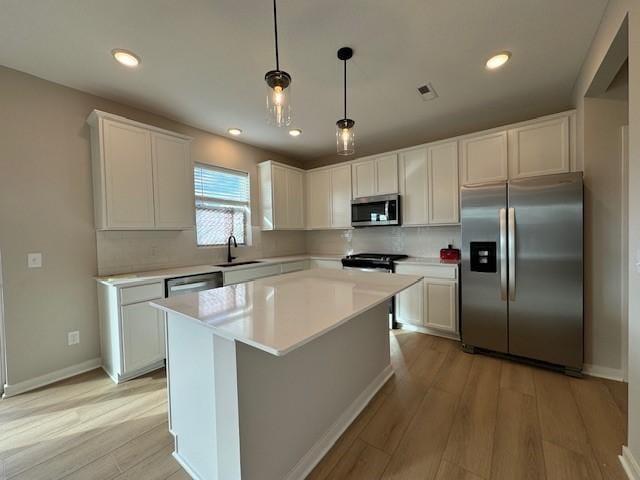 kitchen with white cabinets, appliances with stainless steel finishes, a sink, light wood-style flooring, and visible vents