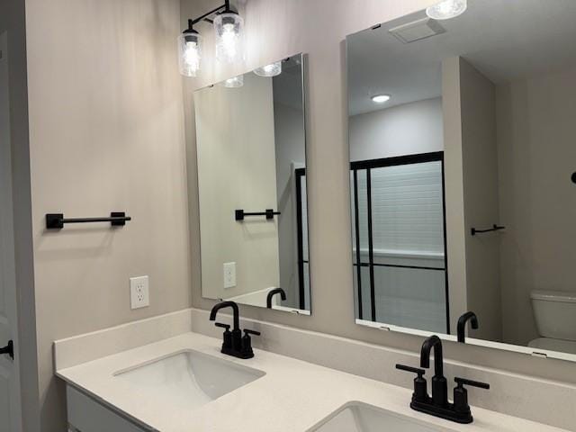bathroom with double vanity, a sink, visible vents, and toilet