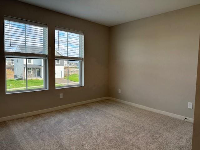 carpeted empty room featuring baseboards