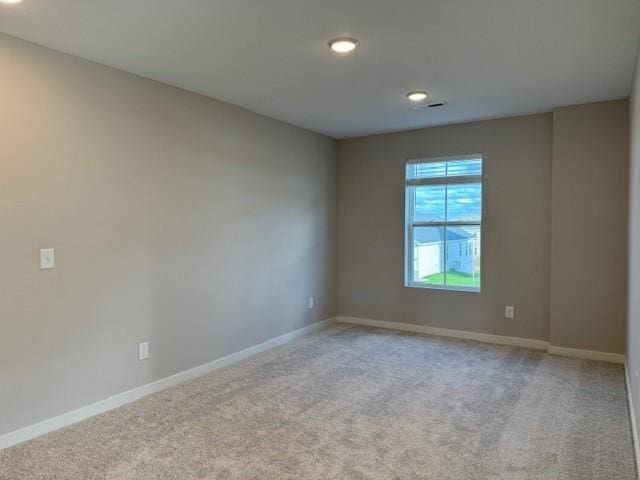spare room featuring light colored carpet, recessed lighting, baseboards, and visible vents
