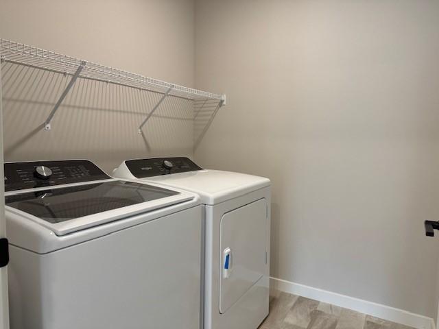 clothes washing area featuring separate washer and dryer, laundry area, and baseboards