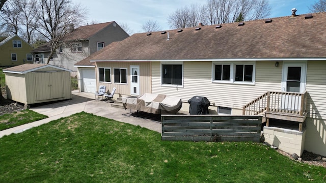 back of property with roof with shingles, a storage unit, a patio, and a lawn