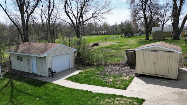 view of yard with a garage, a shed, an outbuilding, and fence