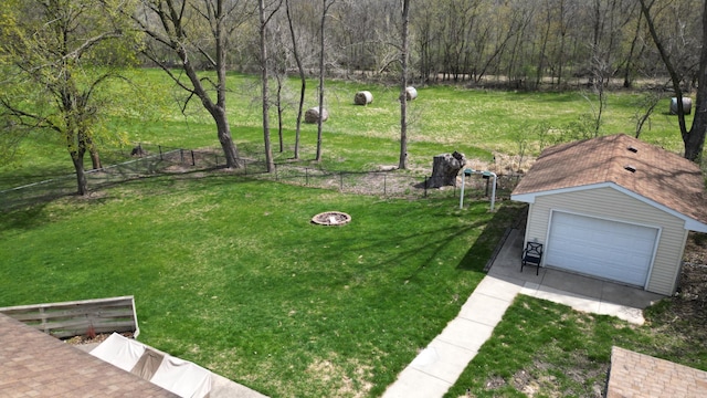 view of yard featuring a fenced backyard, a detached garage, an outdoor structure, and driveway
