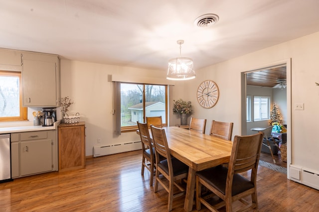 dining room featuring baseboard heating, a baseboard heating unit, wood finished floors, and visible vents