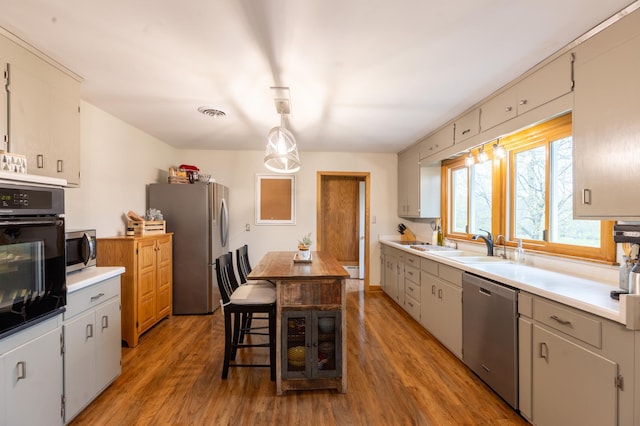 kitchen featuring light countertops, stainless steel appliances, a sink, and light wood finished floors