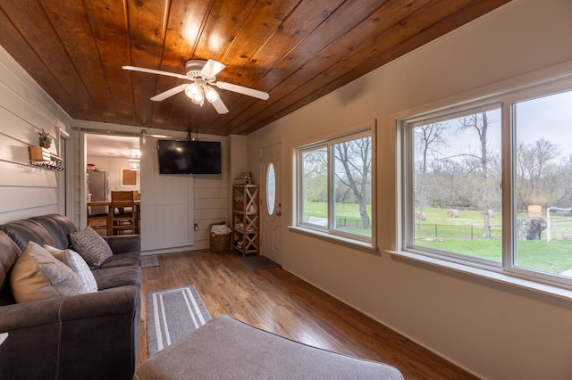 living area with baseboards, wood ceiling, ceiling fan, and wood finished floors