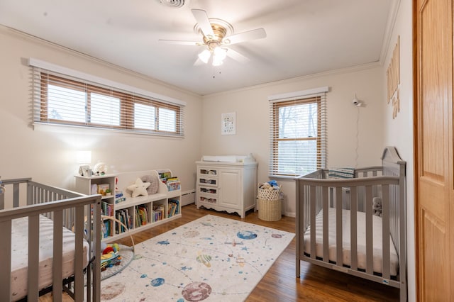bedroom with visible vents, ornamental molding, a baseboard heating unit, and wood finished floors