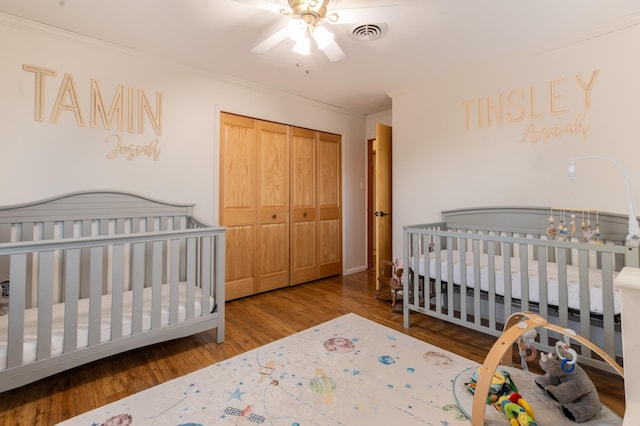 bedroom featuring ornamental molding, a closet, wood finished floors, and visible vents