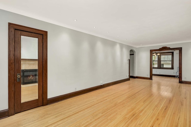 1287 Avon St N, Saint Paul, MN 55117 - empty room featuring arched walkways, light wood finished floors, baseboards, a glass covered fireplace, and recessed lighting