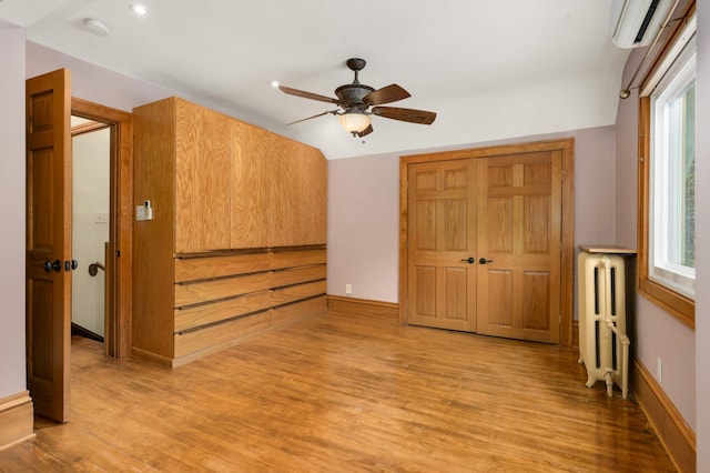 1287 Avon St N, Saint Paul, MN 55117 - unfurnished bedroom featuring radiator, light wood finished floors, a wall mounted air conditioner, multiple windows, and recessed lighting
