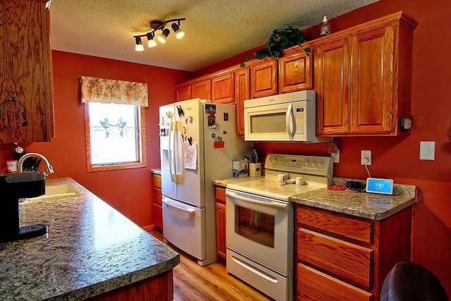 222 Sargent Dr Unit 102, Red Wing, MN 55066 - kitchen featuring brown cabinetry, a textured ceiling, a sink, white appliances, and light wood-style flooring
