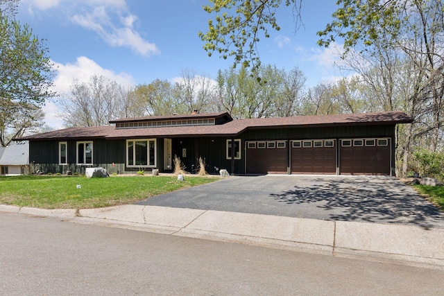 prairie-style house featuring an attached garage, aphalt driveway, a shingled roof, board and batten siding, and a front yard