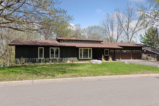 prairie-style house with a front yard, a shingled roof, a garage, and driveway
