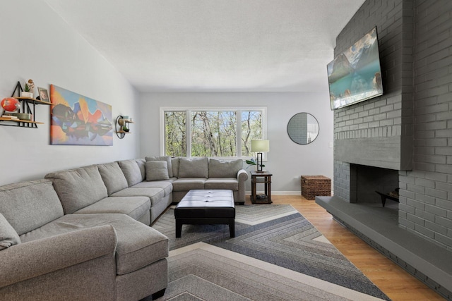 living area with wood finished floors, a fireplace, and baseboards