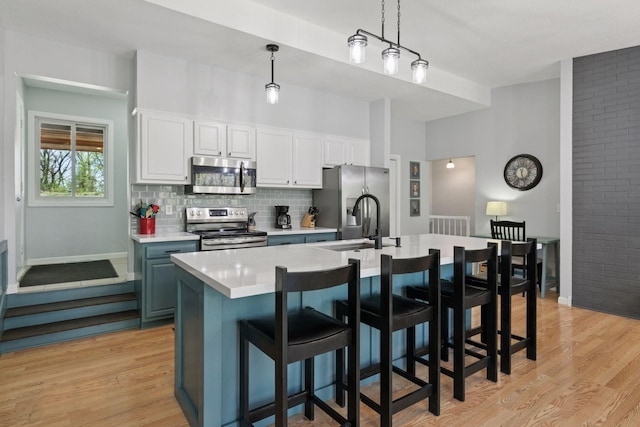 kitchen featuring light wood-type flooring, baseboards, light countertops, and appliances with stainless steel finishes