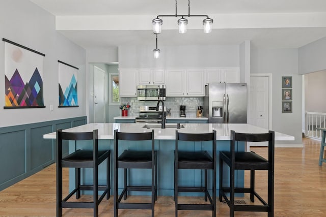 kitchen featuring a sink, white cabinetry, light countertops, appliances with stainless steel finishes, and decorative backsplash