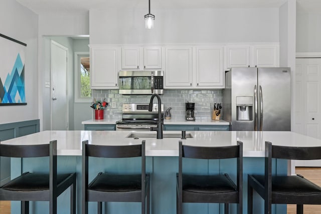 kitchen featuring a sink, white cabinets, light countertops, appliances with stainless steel finishes, and tasteful backsplash