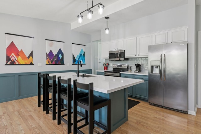 kitchen featuring light wood-type flooring, light countertops, appliances with stainless steel finishes, and a sink