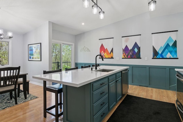 kitchen with green cabinets, light countertops, light wood-type flooring, and a sink