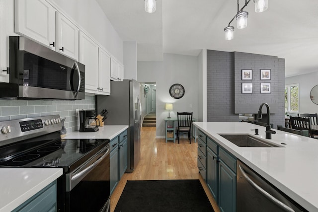 kitchen featuring a sink, stainless steel appliances, white cabinetry, light countertops, and light wood-style floors