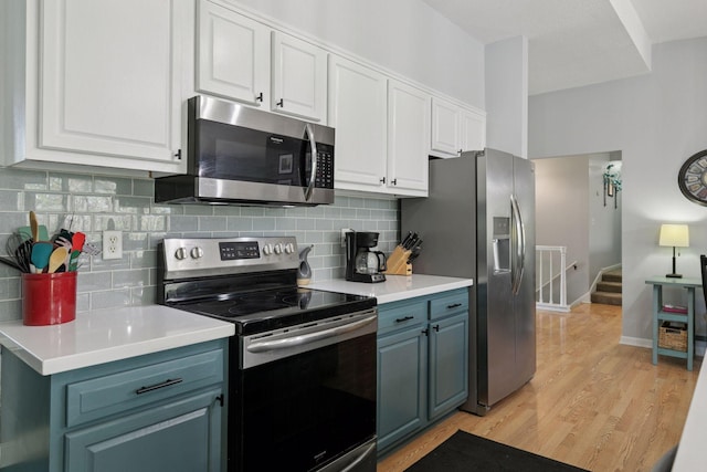 kitchen featuring stainless steel appliances, white cabinets, light wood-type flooring, and tasteful backsplash