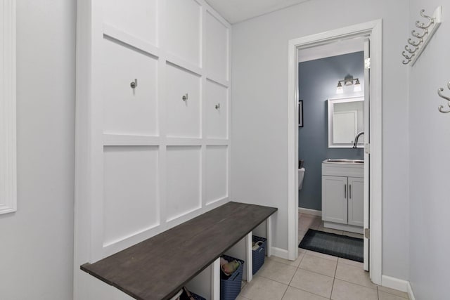 mudroom with light tile patterned floors, baseboards, and a sink