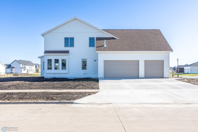 view of front of house with a garage, a shingled roof, and concrete driveway