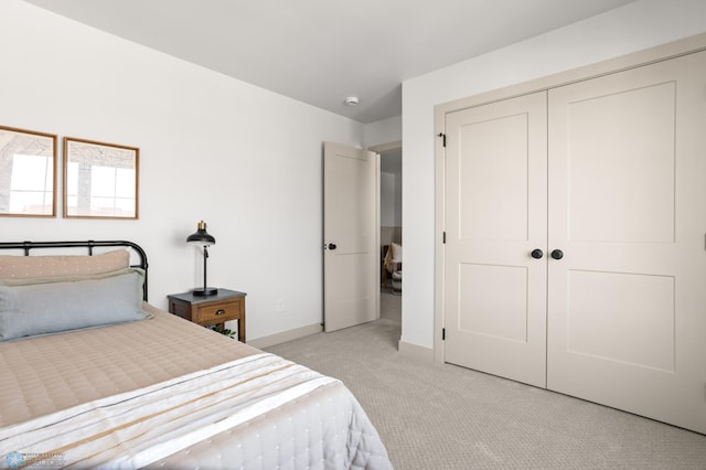 bedroom with baseboards, light colored carpet, and a closet
