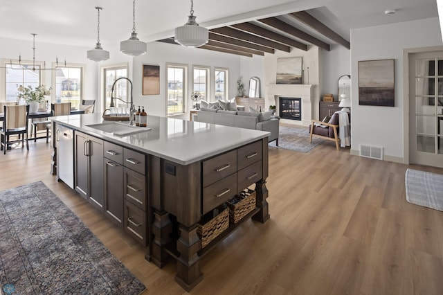 kitchen with hanging light fixtures, a sink, wood finished floors, beamed ceiling, and visible vents