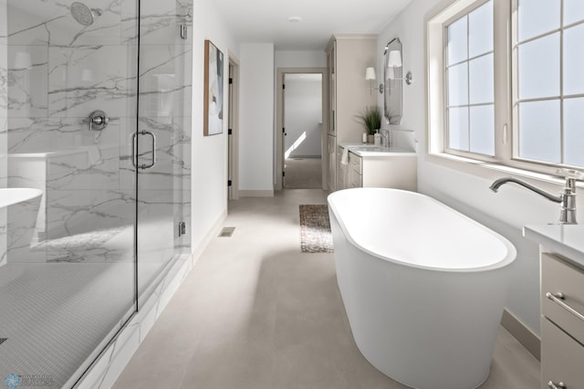 full bath with vanity, a marble finish shower, a freestanding bath, and visible vents