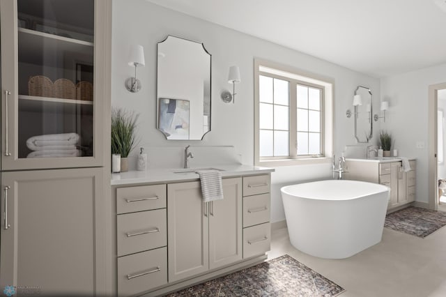 full bathroom with a sink, a soaking tub, and two vanities