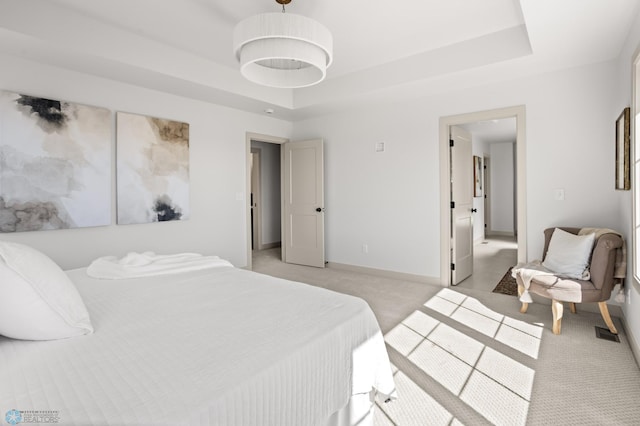 bedroom featuring baseboards, a raised ceiling, and light carpet