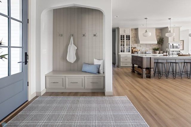 mudroom with a sink, baseboards, light wood-type flooring, recessed lighting, and arched walkways