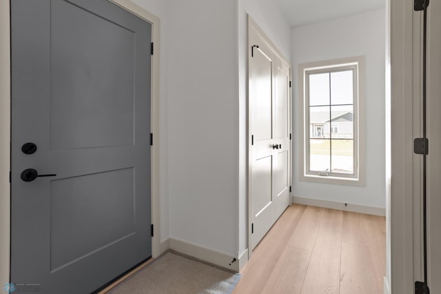 doorway with baseboards and light wood-type flooring