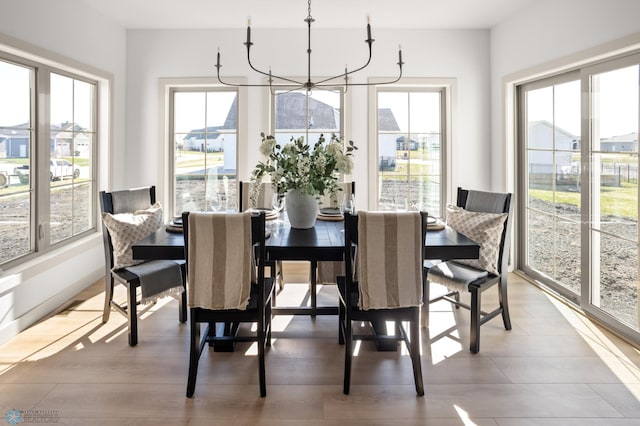 dining space featuring plenty of natural light, wood finished floors, and a notable chandelier
