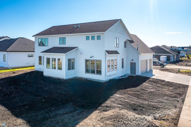 rear view of house with a garage, a shingled roof, and aphalt driveway