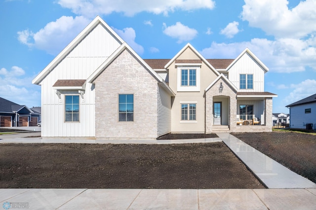 view of front of house featuring covered porch, stone siding, and board and batten siding