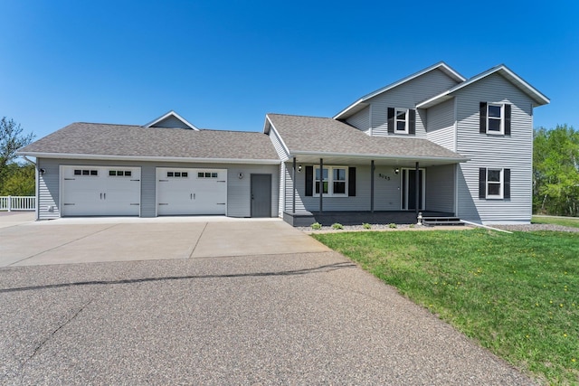 traditional-style home featuring an attached garage, concrete driveway, a front yard, covered porch, and a shingled roof