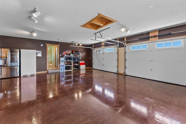 garage featuring stainless steel fridge, baseboards, and white refrigerator