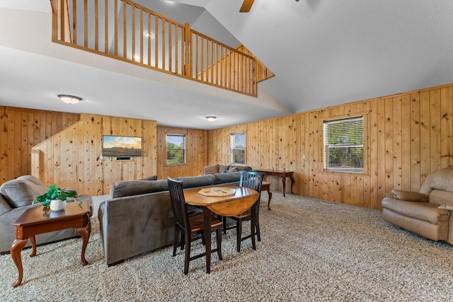 carpeted living area with wood walls, vaulted ceiling, and a ceiling fan