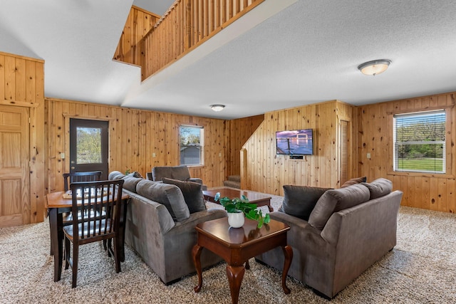 living area with light colored carpet, wood walls, and a textured ceiling