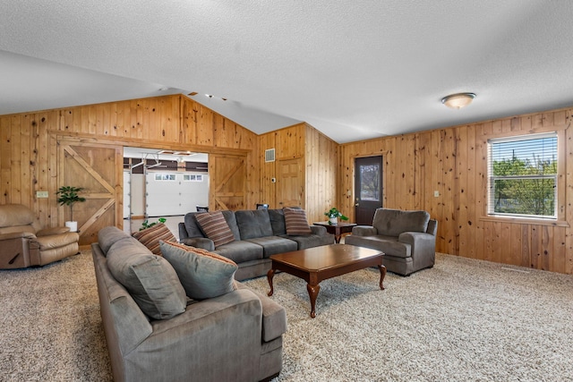carpeted living room with lofted ceiling, wood walls, and a textured ceiling