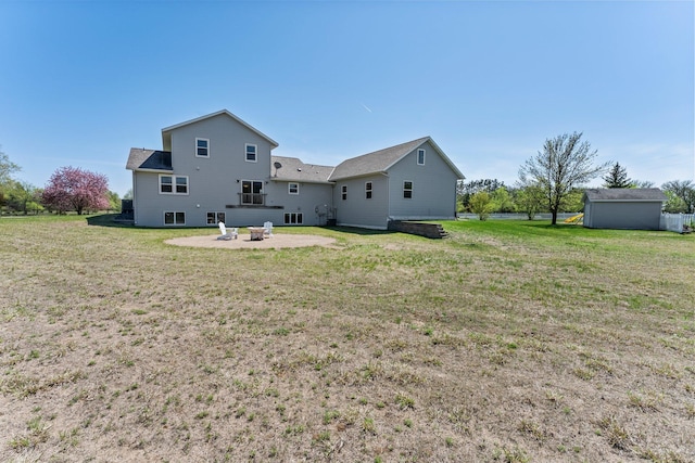 rear view of property with a patio, a lawn, and a fire pit