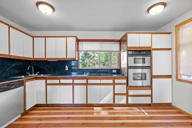 1791 Lois Dr, Shoreview, MN 55126 - kitchen featuring appliances with stainless steel finishes, a textured ceiling, a sink, white cabinetry, and tasteful backsplash