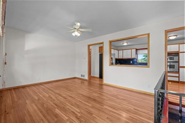 1791 Lois Dr, Shoreview, MN 55126 - unfurnished living room featuring ceiling fan, wood finished floors, baseboards, and a sink