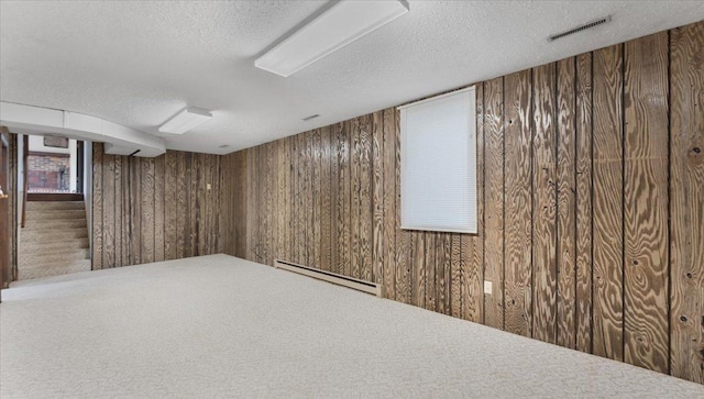 finished basement featuring baseboard heating, a textured ceiling, and wooden walls