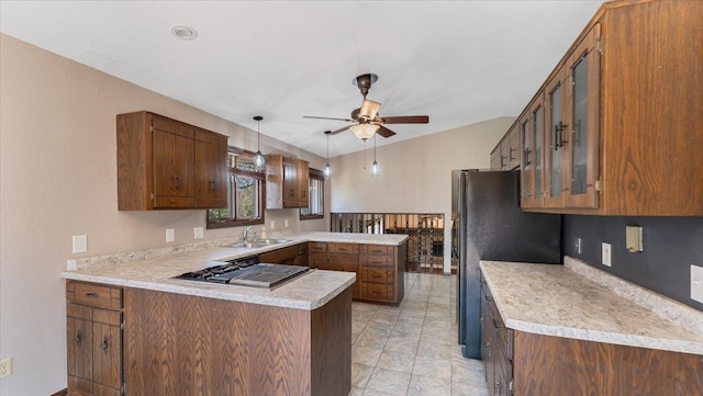 kitchen with a peninsula, freestanding refrigerator, light countertops, ceiling fan, and stovetop with downdraft