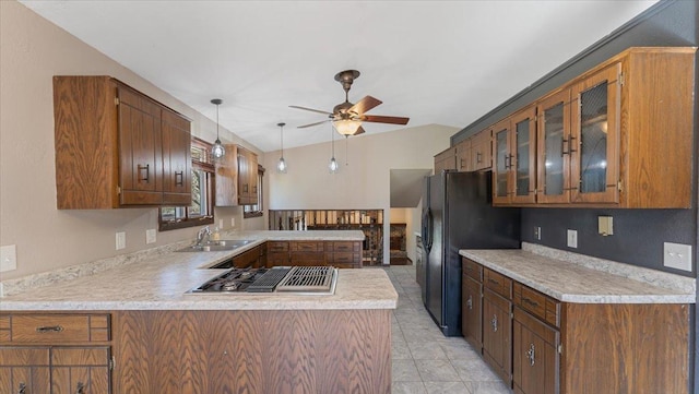 kitchen with stovetop with downdraft, freestanding refrigerator, a sink, a ceiling fan, and a peninsula